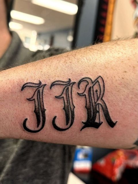 Blackletter initials forearm tattoo