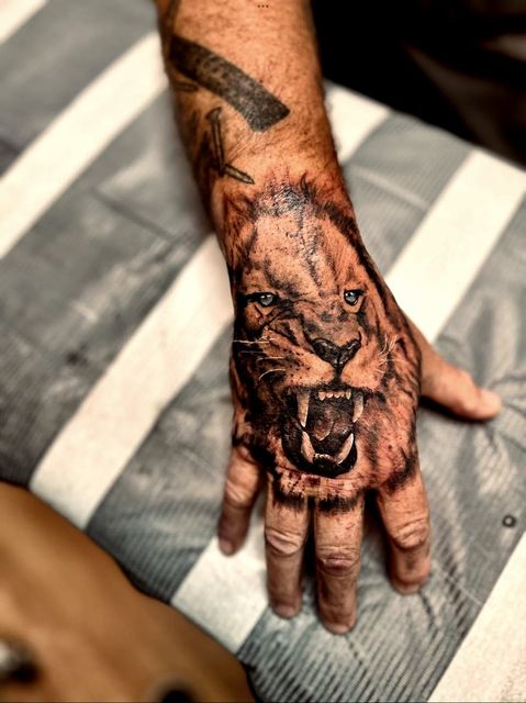 Black and grey lion hand tattoo